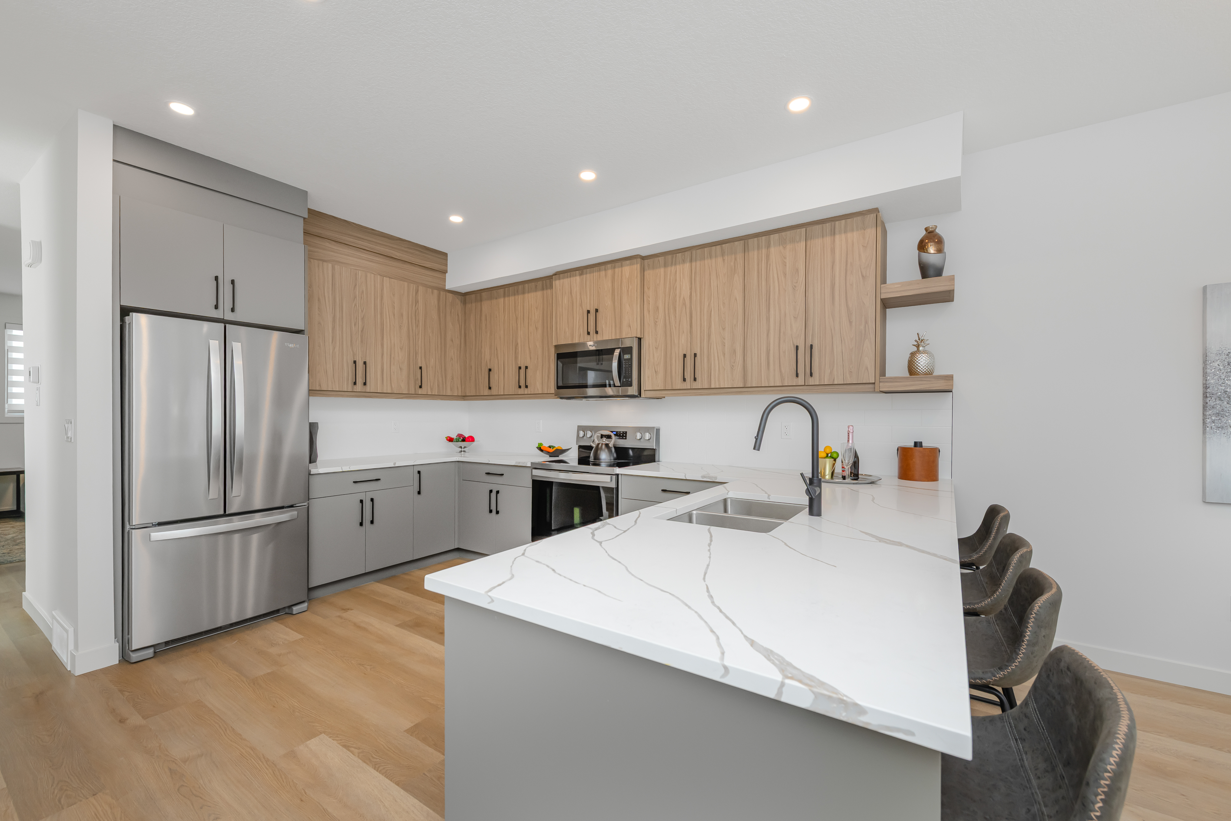 Kitchen with a quartz waterfall island and two-tone cabinetry.
